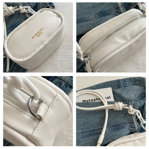 Detail view of white PU leather crossbody bag with gold text and silver hardware accents