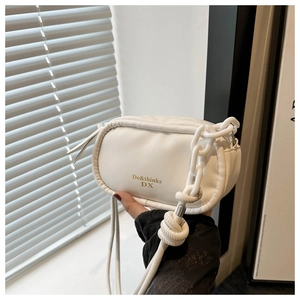 Close-up of white leather handbag featuring bold chunky chain and gold logo detail