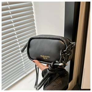 Detail of black faux leather crossbody bag with gold logo text and chunky chain strap