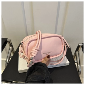 Detailed close-up of a pink square shoulder bag with chain and knotted strap details