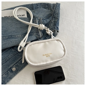 Close-up of white PU leather crossbody bag with gold text detail and knotted strap accents