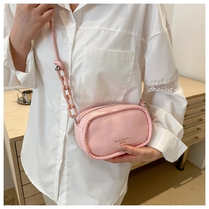 Pink crossbody bag with glossy finish and thick chain detail worn by a model