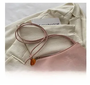 Détail du sac à bandoulière en cuir souple rose avec des perles d'ambre orangées
