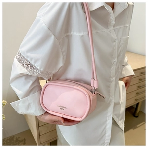 Detail view of pink PU leather crossbody bag with brand logo and zipper on shoulder