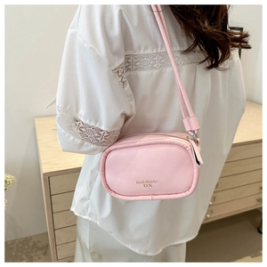 Detail shot of light pink small crossbody bag showing leather texture and gold logo