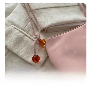 Détail du sac à bandoulière en cuir souple rose avec perles d'ambre et fine lanière