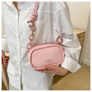 Detail of pink oval crossbody bag with gold logo and thick chain strap on model