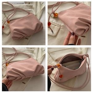 Détails du sac nuage rose montrant la texture plissée, les perles d'ambre et la doublure