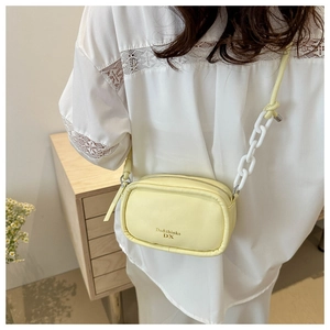 Detail of a mini square yellow crossbody bag with white plastic chain and matte finish