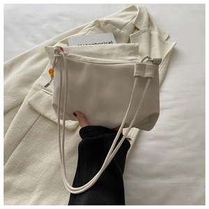 Détail d'un sac bandoulière en cuir blanc crème avec des perles décoratives ambrées