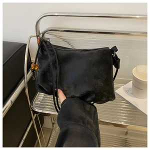 Détail d'un sac à bandoulière en cuir souple avec perles ambrées sur étagère