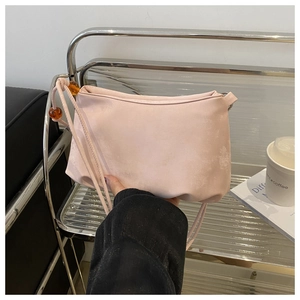 Détail d'un sac bandoulière rose en suédine avec des perles ambrées sur la sangle