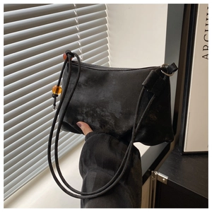 Détail du sac hobo noir texturé avec perles ambrées et fines bandoulières doubles
