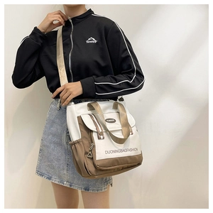 Detail of a white and brown patchwork tote bag with woven shoulder strap on a model