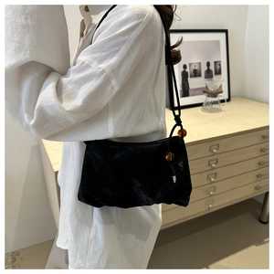 Detalle del bolso de hombro con cuentas ámbar y textura suave tipo terciopelo