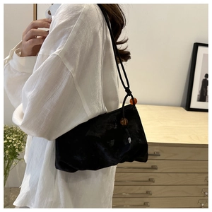 Detalle de bolso nube de terciopelo negro con textura plisada y cuentas de ámbar