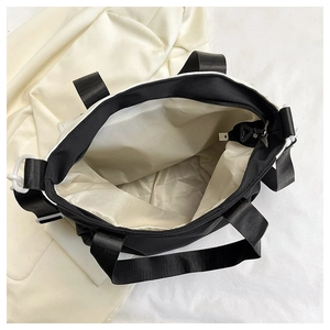 Detail view of large black nylon tote bag showing spacious beige interior with zipper