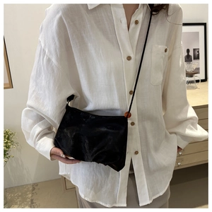 Détail d'un sac bandoulière en velours noir orné d'une perle orange sur la bandoulière