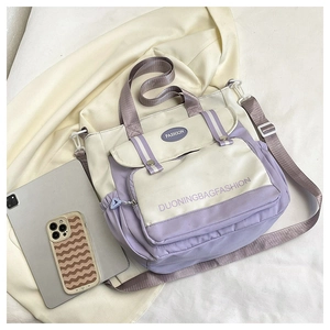 Close-up of stylish two-tone beige and purple shoulder bag with front flap pocket detail