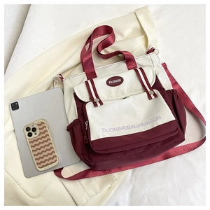 Detail of color-block canvas tote bag with front pockets and wide webbing handles