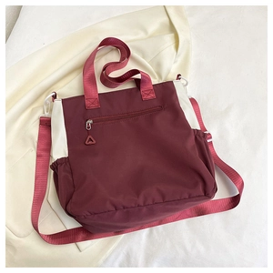 Detail of burgundy and beige tote bag with front zipper and adjustable strap