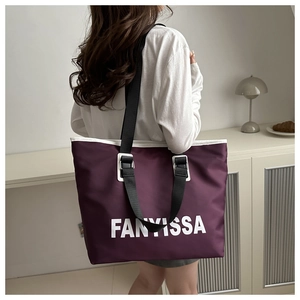 Detail of purple Oxford tote bag with white FANYISSA lettering and wide black nylon strap