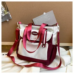 Detail of burgundy and white patchwork shoulder bag showing large front pocket and straps