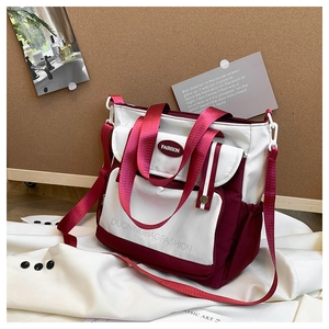 Detail of red and white canvas tote bag with front pocket and adjustable strap