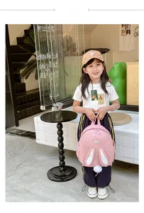 Detailed view of pink school backpack with bunny ears and white plush pom-poms