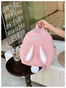 Close-up of pink backpack with cute white rabbit ears and plush pom-pom tail detail