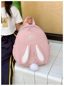 Close-up of cute pink bunny backpack with 3D rabbit ears and a white fluffy pompom tail