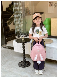 Pink backpack with white bunny ears and pom-pom tail detail worn by a young girl