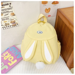 Detail of yellow rabbit backpack featuring long ears and soft white plush pom-pom tail