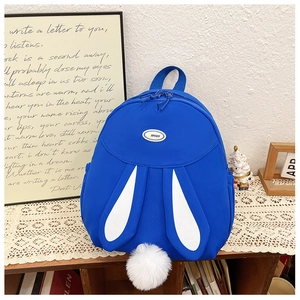 Detail of navy blue school backpack with cute rabbit ears and fluffy pom-pom charm