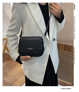 Sac bandoulière noir moderne porté avec un blazer blanc pour un look quotidien chic