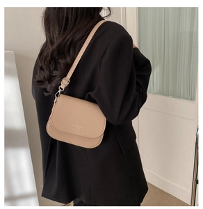 Détail du sac selle kaki avec petit texte blanc imprimé et boucle en métal argenté