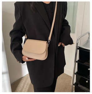 Beige faux leather saddle bag worn with a black blazer for a stylish daily commute look