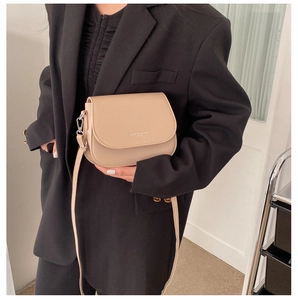 Détail du sac selle beige avec mousquetons métalliques argentés et bandoulière en cuir