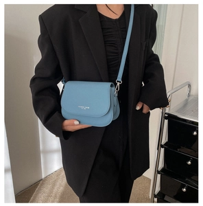 Gros plan sur le sac bandoulière bleu clair avec logo tendance et crochets argentés