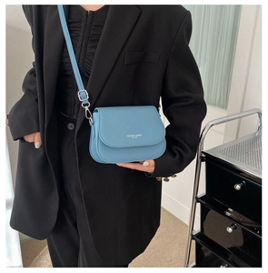 Detail view of a light blue leather saddle bag featuring white printed text on the flap