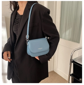 Blue faux leather saddle bag with Fashion Trend logo shown on a black blazer