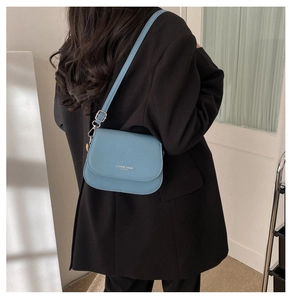 Detail of light blue saddle bag with silver lettering on black blazer background
