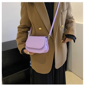 Sacoche lavande en cuir avec bandoulière réglable portée par un mannequin en manteau marron