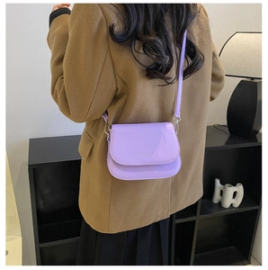 Detail view of purple leather saddle bag with silver hardware on adjustable strap