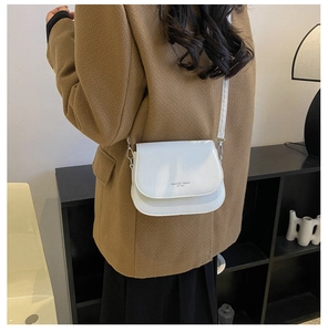 Close-up of white crossbody saddle bag with Fashion Trend 1990 text worn by a model