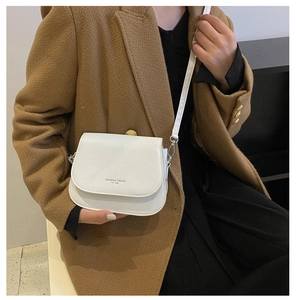 Close-up of white matte leather saddle bag with Fashion Trend text on a model