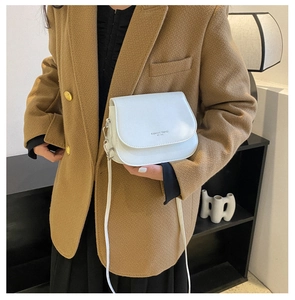 Détail du sac selle blanc avec inscription Fashion Trend porté sur un blazer marron