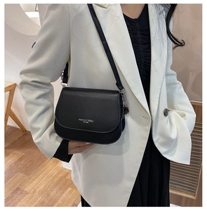Modèle portant un sac bandoulière noir minimaliste avec une gravure argentée élégante