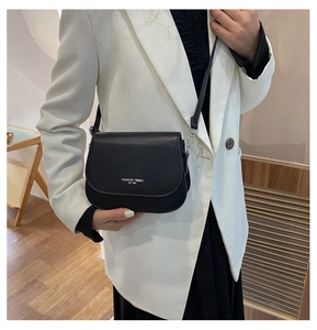 Détail d'un sac besace noir minimaliste avec texte blanc imprimé sur cuir mat