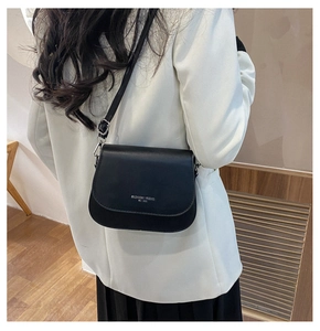 Fashion saddle bag in black matte leather with silver lettering shown on a model